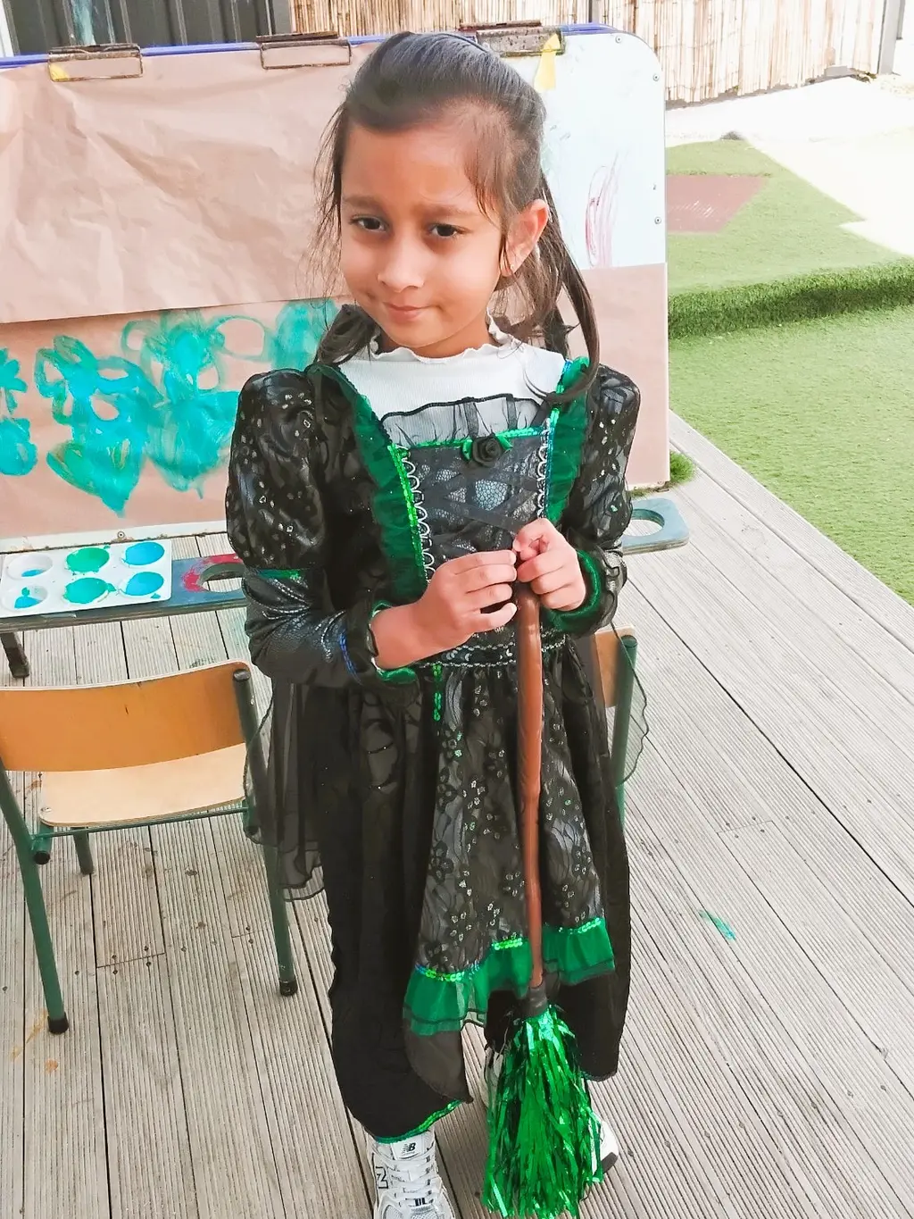 Child wearing a green costume in the outdoor play area