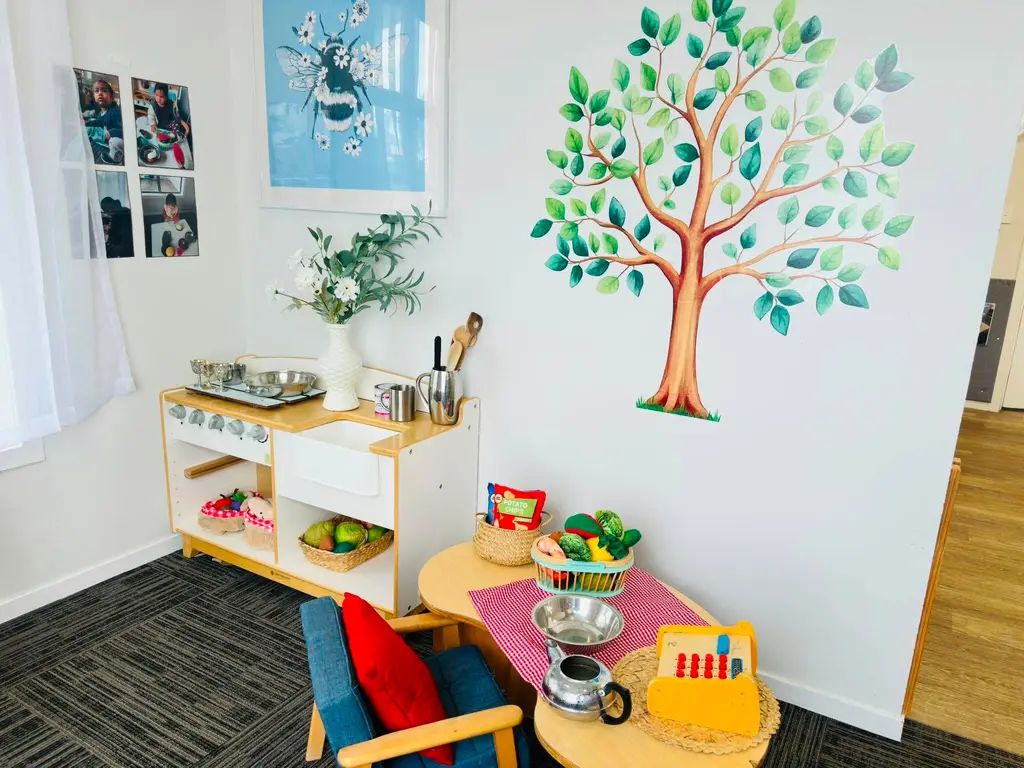 Pretend kitchen and family-play corner beneath a painted tree