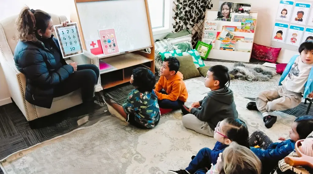 Kaiako sharing a book with tamariki seated together
